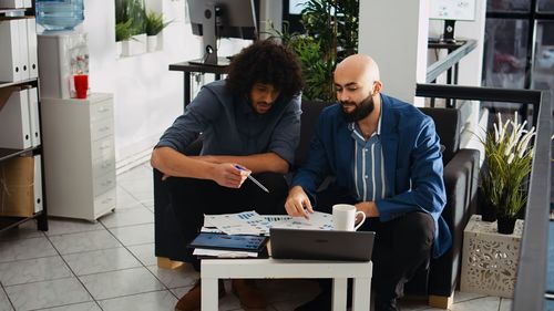 Portrait of young man using mobile phone while sitting in office