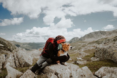 Girl sitting on rock against mountains with her beagle dog