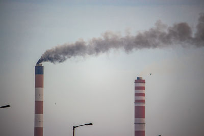 Smoke emitting from chimney against sky