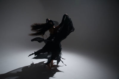 Full length of woman dancing against white background