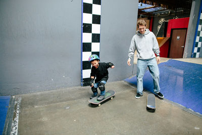 Skateboard student skates on instructor's skateboard, both smile