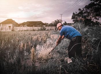 Side view of man standing on field against sky