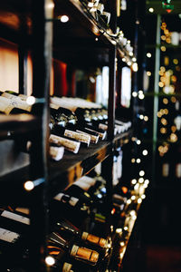Wine bottles arranged on illuminated shelf during christmas