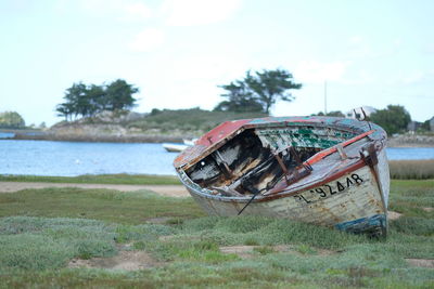 Abandoned boat on land against sky