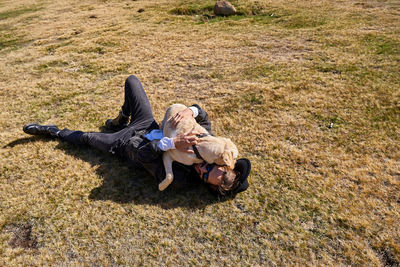 Young tattoed man playing with his dog in the countryside