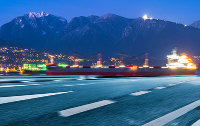 Illuminated city street against sky at night