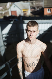 Portrait of shirtless young man standing indoors