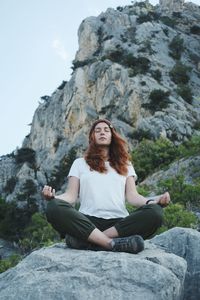 Full length of woman sitting on rock