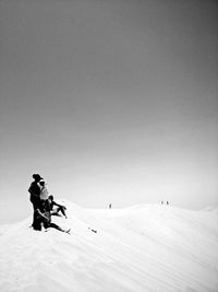 Man skiing on snowy landscape against clear sky