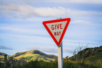 Information sign by road against sky