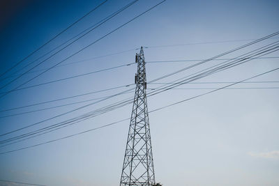 Low angle view of electricity pylon against clear blue sky