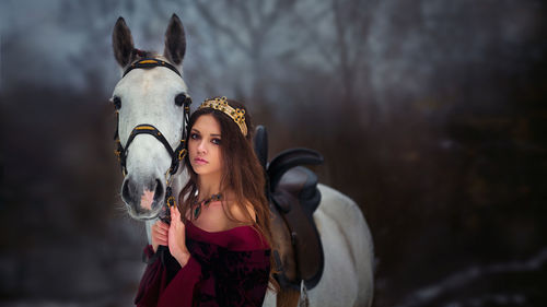 Portrait of young woman with horse standing outdoors