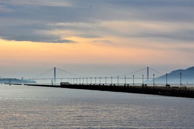 Bridge over sea against sky during sunset