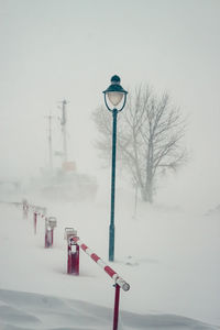 Snow covered street light against sky