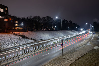 Light trails on road in city at night during winter