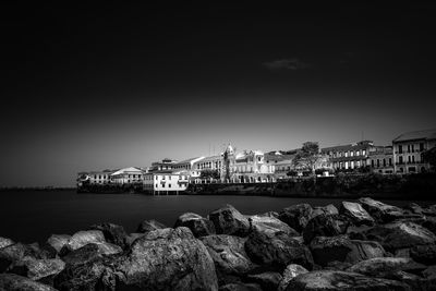 City by sea against clear sky at night