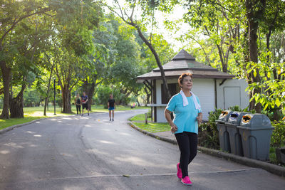 Senior woman running on road against trees at park
