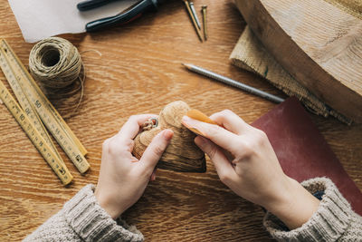 Cropped hands of woman carving wood at table