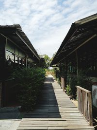 Footpath amidst houses and building against sky