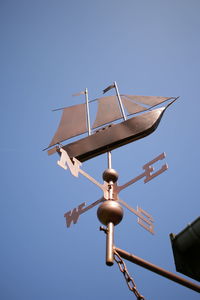 Low angle view of weather vane against clear blue sky