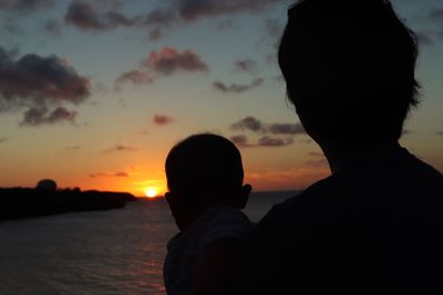 Rear view of silhouette father and son against sky during sunset