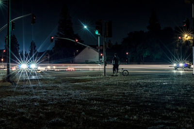 Illuminated light trails on road against sky at night