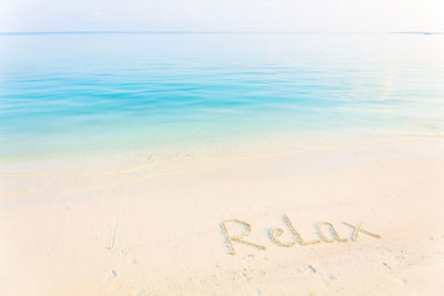 The word relax written in the sand on a beach with morning sea background
