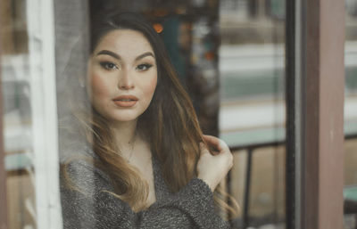 Portrait of young woman looking through window in cafe