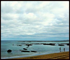 Scenic view of beach against cloudy sky