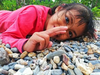 Close-up of girl gesturing while lying on pebble stones