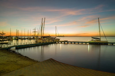 Sailboats in sea at sunset