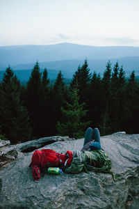 High angle view of person resting on mountain against sky in forest