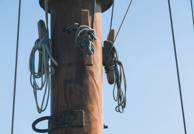 Low angle view of rope hanging on mast against sky