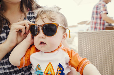 Close-up of mother wearing sunglasses to toddler