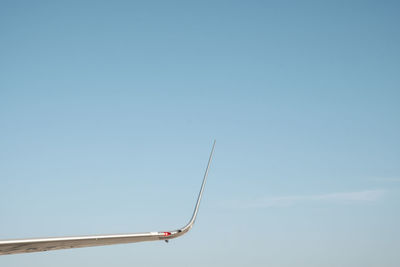 Low angle view of aircraft wing against clear blue sky