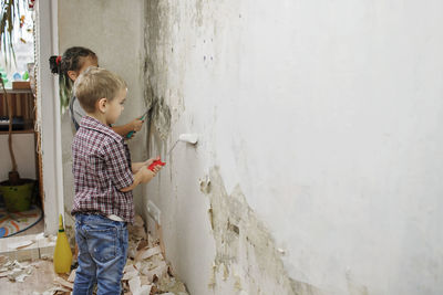 Side view of father and son standing against wall