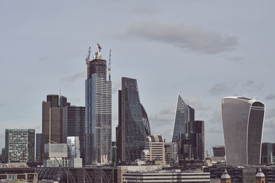 Skyscrapers in city against cloudy sky