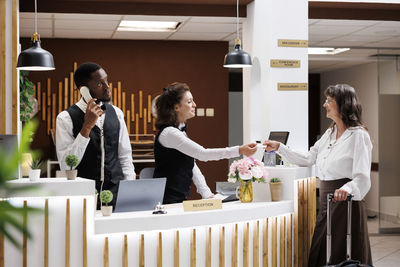 Side view of female friends using mobile phone in meeting