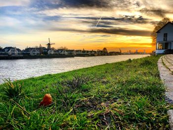 Scenic view of river by buildings against sky during sunset