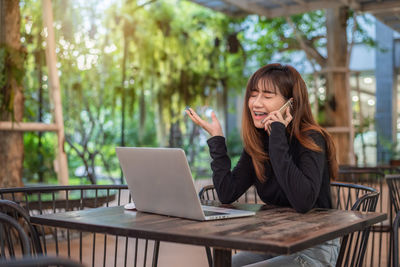 Woman using phone while sitting on table