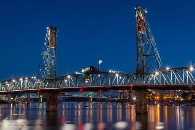 Illuminated bridge against clear blue sky at night