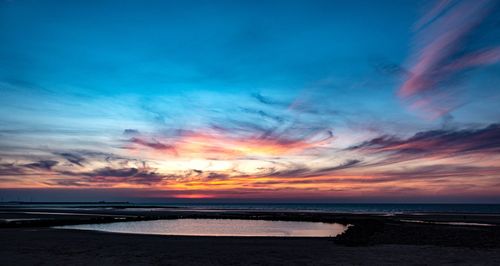 Scenic view of sea against dramatic sky during sunset