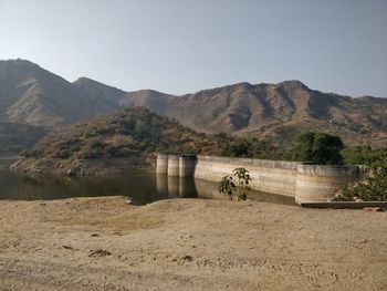 Scenic view of dam and mountains against sky