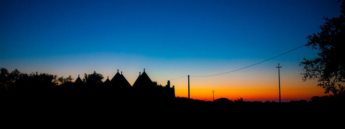 Silhouette buildings against clear sky at sunset