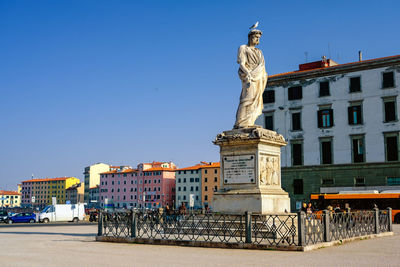 Statue against buildings in city against clear blue sky