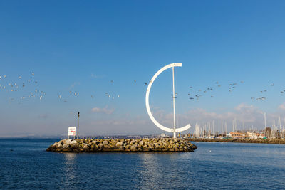 Birds flying over sea against blue sky