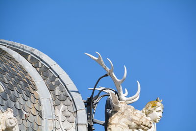 Low angle view of sculptures on roof against clear sky