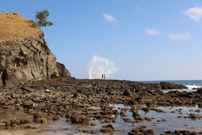 Rock formations on shore against sky