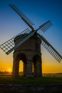 Low angle view of traditional windmill on field against sky