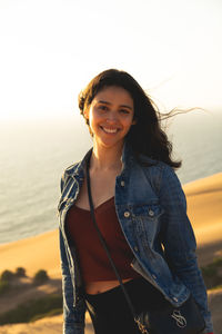 Portrait of smiling young woman standing against sky